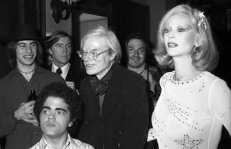 Portrait of American actor Mark Lawhead (left, fore), American Pop artist Andy Warhol (1928 - 1987), and Belgian-born actress Belgian-born actress Monique Van Vooren at the premiere party for the Broadway show 'Man on the Moon' (written by John Phillips and produced by Warhol), held at Sardi's, New York, New York, January 1975. (Photo by Tim Boxer/Getty Images)