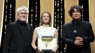 US actress and director Jodie Foster (C) poses on stage with Spanish director Pedro Almodovar (L) and South Korean director Bong Joon-Ho after she received a Palme d'Or Life Achievement Award during the opening ceremony of the 74th edition of the Cannes Film Festival in Cannes, southern France, on July 6, 2021. (Photo by Valery HACHE / AFP) (Photo by VALERY HACHE/AFP via Getty Images)