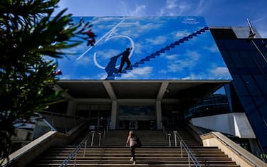 A woman passes by the official poster of the 75th Cannes Film Festival at the Palais des Festivals main entrance in Cannes, southeastern France, on May 16, 2022. - Cannes Film festival will take place from May 17 to May 28. (Photo by PATRICIA DE MELO MOREIRA / AFP) (Photo by PATRICIA DE MELO MOREIRA/AFP via Getty Images)