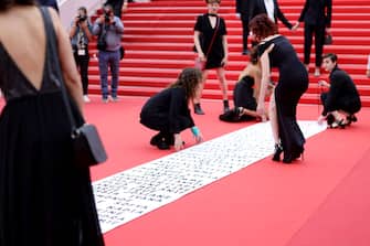 CANNES, FRANCE - MAY 22: Members of the feminist movement "Les Colleuses" hold a banner, displaying the names of 129 women who died as a result of domestic violence ahead of the screening of "Holy Spider" during the 75th annual Cannes film festival at Palais des Festivals on May 22, 2022 in Cannes, France. (Photo by Andreas Rentz/Getty Images)