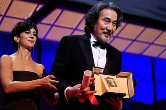 Japanese actor Koji Yakusho (R) stands on stage after he received the Best Actor Prize for his part in the film "Perfect Days" from Iranian actress Zar Amir-Ebrahimi (L) during the closing ceremony of the 76th edition of the Cannes Film Festival in Cannes, southern France, on May 27, 2023. (Photo by Valery HACHE / AFP) (Photo by VALERY HACHE/AFP via Getty Images)