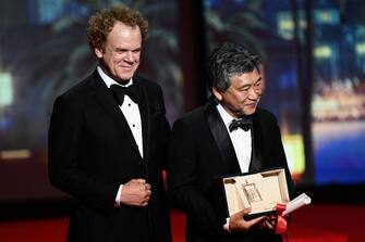 Japanese director Kore-Eda Hirokazu (R) poses on stage with US actor John C. Reilly after he received the Best Screenplay prize for the film "Kaibutsu" (Monster) on behalf of Japanese writer Sakamoto Yuji during the closing ceremony of the 76th edition of the Cannes Film Festival in Cannes, southern France, on May 27, 2023. (Photo by CHRISTOPHE SIMON / AFP) (Photo by CHRISTOPHE SIMON/AFP via Getty Images)