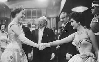 (Original Caption) Gina and the Queen. London, England: Gina Lollobrigida curtseys and shakes hands with Queen Elizabeth II at the royal film premiere of Io Catch a Thief in London. The queen chatted with the Italian actress and other stars, including Ava Gardner, but showed no sign of feeling over Princess Margaret's decision not to marry Peter Townsend. Margaret, who usually attends the annual film performance, remained secluded at Clarence House.