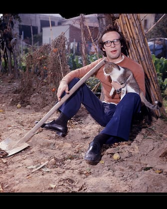 The comedian Roberto Benigni sitting in a field with a shovel and holding a cat. 1976 (Photo by Egizio Fabbrici/Mondadori via Getty Images)