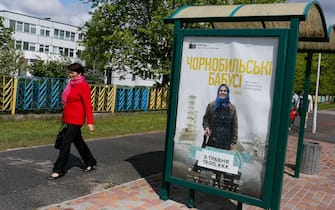 epa05316197 (01/33) A woman walks past a billboard showing the main film of the 'Festival 86' called 'The Babushkas of Chernobyl' by US director Holly Morris, in Slavutich town, some 50 km from the Chernobyl nuclear power plant, Ukraine, 06 May 2016. Slavutich was built for the evacuated personnel of the Chernobyl Nuclear Power Plant and their families after the 1986 disaster. Since 2014 the Festival 86 of film and urbanism takes place in the city annually. This year it was held from 06 to 09 May 2016.  EPA/ROMAN PILIPEY PLEASE REFER TO ADVISORY NOTICE (epa05316196) FOR FULL PACKAGE TEXT