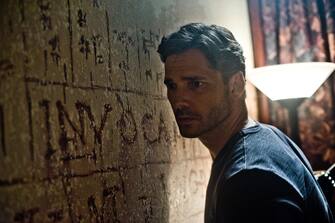 A baffled Sarchie (ERIC BANA) studies the bizarre words and symbols and hears strange sounds from behind the wall in Screen Gems' DELIVER US FROM EVIL.