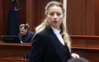 TOPSHOT - US actress Amber Heard (R) speaks to her legal team as US actor Johhny Depp (L) returns to the stand after a lunch recess during the 50 million US dollar Depp vs Heard defamation trial at the Fairfax County Circuit Court in Fairfax, Virginia, April 21, 2022. - Actor Johnny Depp is suing ex-wife Amber Heard for libel after she wrote an op-ed piece in The Washington Post in 2018 referring to herself as a public figure representing domestic abuse. (Photo by Jim LO SCALZO / POOL / AFP) (Photo by JIM LO SCALZO/POOL/AFP via Getty Images)