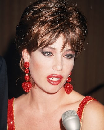 Actor and model Kelly Le Brock speaks into a microphone, wearing red earrings, 1990s. (Photo by Hulton Archive/Getty Images) 