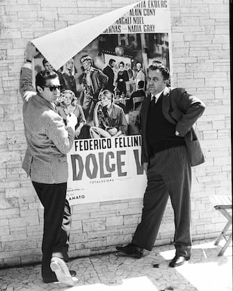 Federico Fellini holds up a poster for his film "La Dolce Vita", with Marcello Mastroianni, ca. 1960.   (Photo by David Lees/Corbis/VCG via Getty Images)