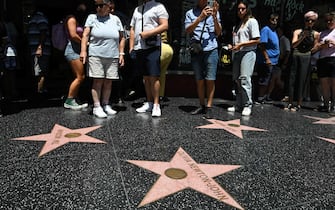 People view the star of Australian singer and actress Olivia Newton-John on the Hollywood Walk of Fame in Hollywood, California, on August 8, 2022. - Australian singer Olivia Newton-John, who gained worldwide fame as high-school sweetheart Sandy in the hit musical movie "Grease," died on August 8, 2022, her family said. She was 73. The entertainer, whose career spanned more than five decades, devoted much of her time and celebrity to charities after being diagnosed with breast cancer in 1992. (Photo by Robyn Beck / AFP)