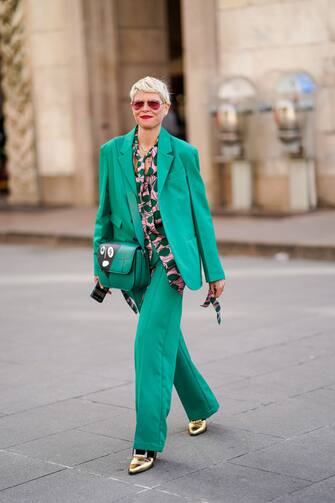 1220560538 MILAN, ITALY - FEBRUARY 20: Elisa Nalin wears red sunglasses, a green oversized blazer jacket, a green and pink shirt, a green leather bag, flared pants, golden pointy shoes, outside Vivetta, during Milan Fashion Week Fall/Winter 2020-2021 on February 20, 2020 in Milan, Italy. (Photo by Edward Berthelot/Getty Images)