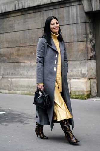 PARIS, FRANCE - FEBRUARY 28: Caroline Issa wears a yellow wool turtleneck woven pullover, a gray long coat, a black leather bag, a yellow lustrous silky skirt, black and yellow snake pattern pointy leather boots, outside Nina Ricci, during Paris Fashion Week - Womenswear Fall/Winter 2020/2021, on February 28, 2020 in Paris, France. (Photo by Edward Berthelot/Getty Images)