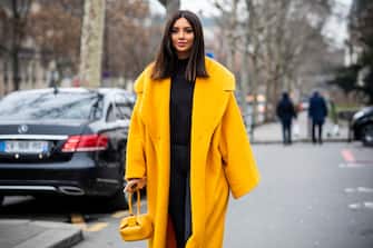 PARIS, FRANCE - JANUARY 20: Nathalie Fanj, wearing a black jumper, black pants, black boots, yellow long coat and yellow bag, is seen in the streets of Paris before the Acne Femme show on January 20, 2019 in Paris, France. (Photo by Claudio Lavenia/Getty Images)