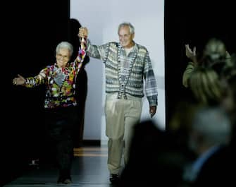 2564079 Italian Tai (R) and Rosita Missoni acknowledge applause on the catwalk at the end of the Missoni collection during the last day of the Milan 2004 Spring/Summer fashion week 05 October 2003. The show is a milestone in every sense as it marks 50 years since the company was founded by Tai and Rosita and 50 years since they married. AFP PHOTO/PAOLO COCCO (Photo credit should read PAOLO COCCO/AFP via Getty Images)