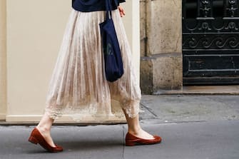 1251683231 PARIS, FRANCE - JUNE 20: A passerby wears a pale pink pleated skirt with embroidery, brown flat shoes, a blue bag, on June 20, 2020 in Paris, France. (Photo by Edward Berthelot/Getty Images)