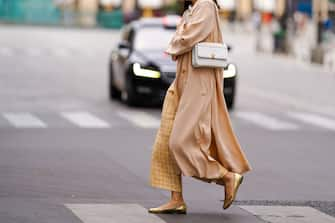 PARIS, FRANCE - JULY 04: A passerby wears yellow checked wool knitted pants, golden flat ballerina shoes, a white Chanel bag, a salmon-pink flowing long coat, on July 04, 2020 in Paris, France. (Photo by Edward Berthelot/Getty Images)