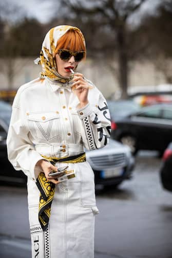 PARIS, FRANCE - MARCH 02: A guest, wearing a white denim Versace jacket with matching Versace skirt, beige boots and printed hair scarf, is seen outside Haider Ackermann on Day 6 Paris Fashion Week Autumn/Winter 2019/20 on March 2, 2019 in Paris, France. (Photo by Claudio Lavenia/Getty Images)