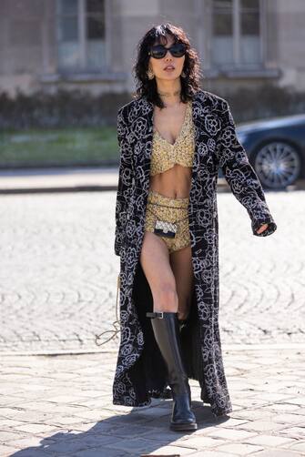 1384294761 PARIS, FRANCE - MARCH 08: Xia Yan wearing a braided yellow top with matching shorts, black and white printed coat, Chanel mini belt bag, black boots and yellow Chanel bag, is seen outside Chanel, during Paris Fashion Week - Womenswear F/W 2022-2023 on March 08, 2022 in Paris, France. (Photo by Claudio Lavenia/Getty Images)