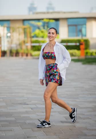 DUBAI, UNITED ARAB EMIRATES - MARCH 29: Ann-Kathrin GÃ¶tze is seen wearing Set Valentino, cropped top, shorts with logo print, sneaker in black white Nike, necklace Van cleef & arpels, white button shirt on March 29, 2022 in Dubai, United Arab Emirates. (Photo by Christian Vierig/Getty Images)