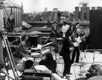 30th January 1969: British rock group the Beatles performing their last live public concert on the rooftop of the Apple Organization building for director Michael Lindsey-Hogg's film documentary, 'Let It Be,' on Savile Row, London, England.  Drummer Ringo Starr sits behind his kit of him.  Singer / songwriters Paul McCartney and John Lennon perform at their microphones, and guitarist George Harrison (1943 - 2001) stands behind them.  Lennon's wife Yoko Ono sits at right.  (Photo by Express / Express / Getty Images)