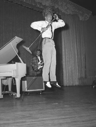 (Original Caption) 6/10/58-New York: His prodigious head of hair standing on end, rock 'n' roll roller Jerry Lee Lewis hugs the microphone as he does a flying leap during his opening night performance at the Cafe de Paris, here June 10th. He revealed that he had remarried his 13-year-old bride Myra just to "satisfy the people in the U.S. and England" that everything was legal.