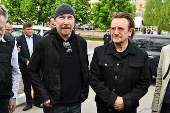 TOPSHOT - Bono (R) (Paul David Hewson), activist and front man of the Irish rock band U2 and guitarist David Howell Evans aka 'The Edge' (L) visits the site of a mass grave by the Church of St. Andrew Pervozvannoho All Saints in the Ukrainian town of Bucha, near Kyiv on May 8, 2022. (Photo by Genya SAVILOV / AFP) (Photo by GENYA SAVILOV/AFP via Getty Images)