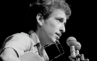 Close-up of American musician Bob Dylan as he plays acoustic guitar during a performance at the Newport Folk Festival, Newport, Rhode Island, July 1963. (Photo by Rowland Scherman/Getty Images)