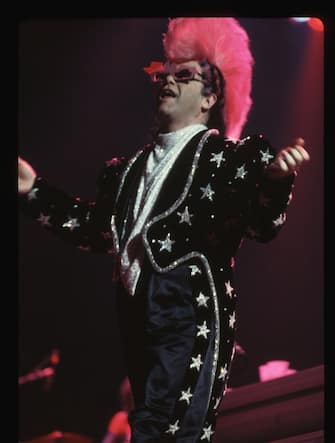 Singer Elton John performs wearing a tuxedo decorated with silver stars and a pink mohawk.   (Photo by Lynn Goldsmith/Corbis/VCG via Getty Images)