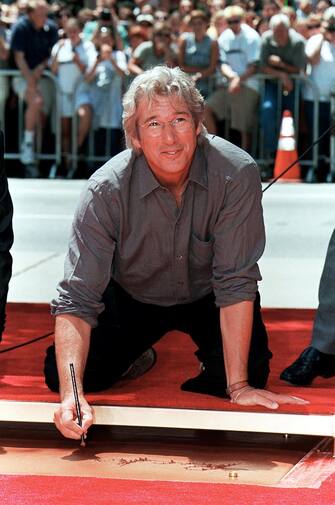 HOLLYWOOD, :  US actor Richard Gere signs his name before placing his hands and feet in cement during a ceremony 26 July 1999 at Mann's Chinese Theatre in Hollywood, Ca.  Gere, who has starred in films such as "Pretty Woman", "Officer and a Gentleman"  and "Red Corner", is currently featured with Julia Roberts in the romantic-comedy "Runaway Bride."  AFP PHOTO/Vince BUCCI (Photo credit should read Vince Bucci/AFP via Getty Images)