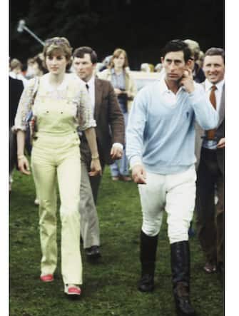 COWDRAY PARK, ENGLAND - JULY 12: Lady Diana Spencer, wearing yellow dungarees with a floral blouse and red wedges, walks with her future husband Britain's Prince Charles, Prince of Wales, at the Cowdray Park Polo Club days before her marriage to the Prince, on July 12, 1981 in Gloucestershire, United Kingdom. (Photo by Anwar Hussein/WireImage)