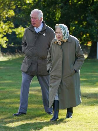 CRATHIE,  UNITED KINGDOM - OCTOBER 1:  Queen Elizabeth II and Prince Charles, Prince of Wales (known as the Duke of Rothesay when in Scotland) walk to the Balmoral Estate Cricket Pavilion to mark the start of the official planting season for the Queen's Green Canopy (QGC) at the Balmoral Estate on October 1, 2021 near Crathie, Scotland. The QGC is a UK-wide Platinum Jubilee initiative which will create a lasting legacy in tribute to the Queen's 70 years of service to the nation, through a network of trees planted in her name. (Photo by Andrew Milligan-WPA Pool/Getty Images)