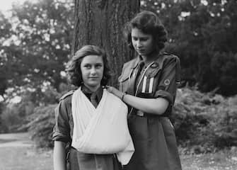 Princess Elizabeth places Princess Margaret's arm in a sling as part of the girl guides in Frogmore, Windsor, England on April 11, 1942.  (Photo by Studio Lisa/Getty Images)
