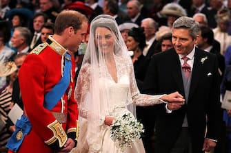 113265077 LONDON, ENGLAND - APRIL 29: Prince William speaks to his bride, Catherine Middleton as she holds the hand of her father Michael Middleton at Westminster Abbey on April 29, 2011 in London, England. The marriage of Prince William, the second in line to the British throne, to Catherine Middleton is being held in London today. The marriage of the second in line to the British throne is to be led by the Archbishop of Canterbury and will be attended by 1900 guests, including foreign Royal family members and heads of state. Thousands of well-wishers from around the world have also flocked to London to witness the spectacle and pageantry of the Royal Wedding. (Photo by Dominic Lipinski - WPA Pool/Getty Images)