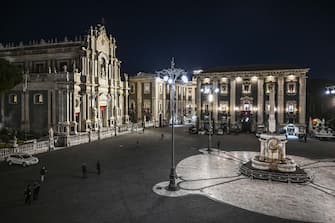 1300386386 CATANIA, ITALY - FEBRUARY 04: Piazza del Duomo empty and without devotees to limit the risk of crowds of devotees in front of the cathedral housing St Agatha's relics on February 4, 2021 in Catania, Italy. A couple of devotees look at the window of a shop in the centre of Catania with the statue of Saint Agatha on February 4, 2021 in Catania, Italy. The Feast of the patron saint of the city of Catania, Sant'Agata, has been cancelled because of the Covid19 emergency, which is celebrated on 4 and 5 February each year. Usually, during the Agatha festivities, almost a million people arrive in Catania, including devotees and tourists from every region of Italy and the rest of the world. Disappointment among devotees who will not be able to see their patron saint again. (Photo by Fabrizio Villa/Getty Images)