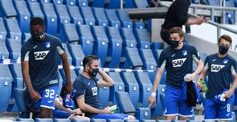 SINSHEIM, GERMANY - MAY 16: Melayro Bogarde of TSG 1899 Hoffenheim and his team mates take their seats on the bench while wearing face masks prior to the Bundesliga match between TSG 1899 Hoffenheim and Hertha BSC at PreZero-Arena on May 16, 2020 in Sinsheim, Germany. The Bundesliga and Second Bundesliga is the first professional league to resume the season after the nationwide lockdown due to the ongoing Coronavirus (COVID-19) pandemic. All matches until the end of the season will be played behind closed doors. (Photo by Thomas Kienzle/Pool via Getty Images)