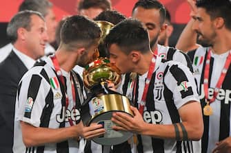 TOPSHOT - Juventus midfielder from Italy Miralem Pjanic and Juventus' forward from Argentina Paulo Dybala (R) kiss the trophy after winning the Italian Tim Cup (Coppa Italia) final Juventus vs AC Milan at the Olympic stadium on May 9, 2018 in Rome. - Juventus crushed AC Milan 4-0 on today at the Stadio Olimpico to win a fourth consecutive Italian Cup. Mehdi Benatia opened the floodgates after 56 minutes for the first of a double of the night for the Moroccan with Douglas Costa also finding the net in the space of nine minutes. A Nikola Kalinic own goal accounted for the fourth (Photo by Tiziana FABI / AFP)        (Photo credit should read TIZIANA FABI/AFP via Getty Images)