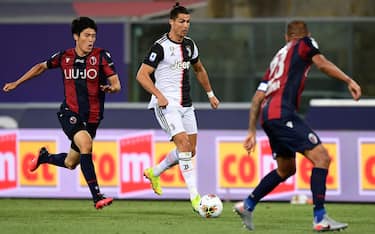 Juventus' Portuguese forward Cristiano Ronaldo (C) outruns Bologna's Japanese defender Takehiro Tomiyasu during the Italian Serie A football match Bologna vs Juventus on June 22, 2020 at the Renato-Dall'Ara stadium in Bologna, as the country eases its lockdown aimed at curbing the spread of the COVID-19 infection, caused by the novel coronavirus. (Photo by Miguel MEDINA / AFP) (Photo by MIGUEL MEDINA/AFP via Getty Images)