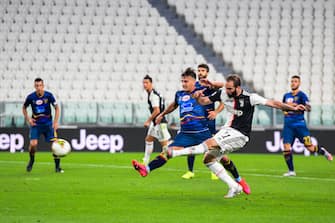 Juventus' Argentinian forward Gonzalo Higuain (R) shoots to score the third goal during the Italian Serie A football match Juventus vs Lecce played on June 26, 2020 behind closed doors at the Juventus stadium in Turin, as the country eases its lockdown aimed at curbing the spread of the COVID-19 infection, caused by the novel coronavirus. (Photo by Miguel MEDINA / AFP) (Photo by MIGUEL MEDINA/AFP via Getty Images)