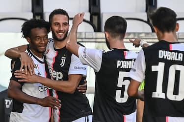 Juventus' Colombian midfielder Juan Cuadrado (L) celebrates with Juventus' Uruguayan midfielder Rodrigo Bentancur (2ndL) after scoring during the Italian Serie A football match Juventus vs Torino played behind closed doors on July 4, 2020 at the Juventus stadium in Turin, as the country eases its lockdown aimed at curbing the spread of the COVID-19 infection, caused by the novel coronavirus. (Photo by Marco BERTORELLO / AFP) (Photo by MARCO BERTORELLO/AFP via Getty Images)