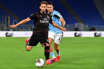AC Milan's Turkish forward Hakan Calhanoglu (L) and Lazio's Spanish defender Patric go for the ball during the Italian Serie A football match Lazio vs AC Milan played behind closed doors on July 4, 2020 at the Olympic stadium in Rome, as the country eases its lockdown aimed at curbing the spread of the COVID-19 infection, caused by the novel coronavirus. (Photo by Tiziana FABI / AFP) (Photo by TIZIANA FABI/AFP via Getty Images)