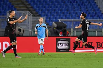 AC Milan's Turkish forward Hakan Calhanoglu (R) celebrates with AC Milan's Swedish forward Zlatan Ibrahimovic (L) after opening the scoring during the Italian Serie A football match Lazio vs AC Milan played behind closed doors on July 4, 2020 at the Olympic stadium in Rome, as the country eases its lockdown aimed at curbing the spread of the COVID-19 infection, caused by the novel coronavirus. (Photo by Tiziana FABI / AFP) (Photo by TIZIANA FABI/AFP via Getty Images)