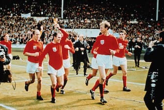 30th July 1966:  Ray Wilson (holding the trophy) performing a lap of honour with the Charlton brothers at Wembley after England won the World Cup against West Germany 4-2.  (Photo by Hulton Archive/Getty Images)
