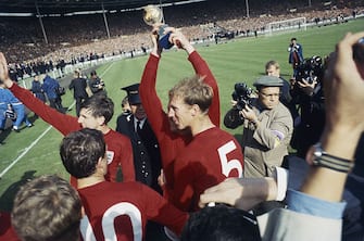 Martin Peters and Jack Charlton celebrate on the pitch after England's victory in the 1966 World Cup final at Wembley, 30th July 1966. Captain Bobby Moore, obscured by Jack Charlton, holds the Jules Rimet trophy aloft. (Photo by Central Press/Hulton Archive/Getty Images)
