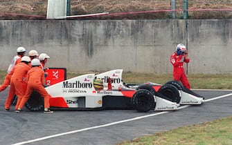 Ayrton Senna of Brazil is given a push from circuit marshals for a restart while his teammate and bitter rival Alain Prost of France leaves his car to abandon the race after the two collided in a chicane during the Japan Formula One Grand Prix in Suzuka 22 October 1989. Senna received the chequered flag but was later disqualified after being accused of receiving an illegal push from marshals and of taking a short cut through the chicane. AFP PHOTO TOSHIFUMI KITAMURA (Photo credit should read TOSHIFUMI KITAMURA/AFP via Getty Images)