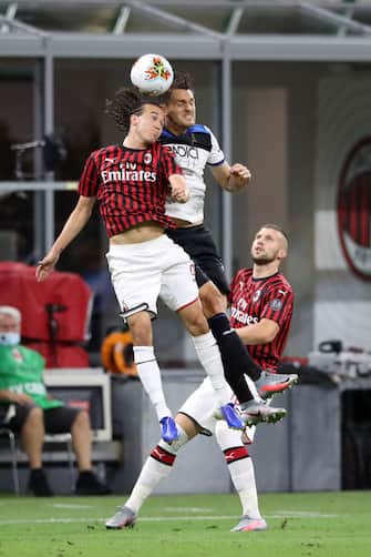 MILAN, ITALY - JULY 24: Diego Laxalt of AC Milan challenges Rafael Toloi of Atalanta for an aerial ball as Ante Rebic of AC Milan looks on during the Serie A match between AC Milan and  Atalanta BC at Stadio Giuseppe Meazza on July 24, 2020 in Milan, Italy. (Photo by Jonathan Moscrop/Getty Images)
