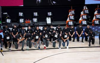 Players kneel during the national anthem before the start of an NBA basketball game between the New Orleans Pelicans and the Utah Jazz Thursday, July 30, 2020, in Lake Buena Vista, Fla. (AP Photo/Ashley Landis, Pool)