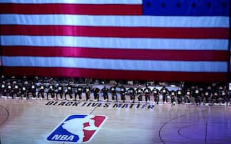 1227859233 LAKE BUENA VISTA, FL - JULY 31: Players kneel behind a Black Lives Matter court decal before the start of a game between the Brooklyn Nets and the Orlando Magic on July 31, 2020 at The HP Field House at ESPN Wide World Of Sports Complex in Lake Buena Vista, Florida. NOTE TO USER: User expressly acknowledges and agrees that, by downloading and/or using this Photograph, user is consenting to the terms and conditions of the Getty Images License Agreement. (Photo by Ashley Landis - Pool/Getty Images)