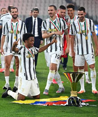 Juventus' Colombian midfielder Juan Cuadrado (L) and his teammates celebrate with the Champion's trophy at the end of the Italian Serie A football match Juventus vs Roma on August 1, 2020 at the Allianz stadium in Turin, Italy. (Photo by Isabella BONOTTO / AFP) (Photo by ISABELLA BONOTTO/AFP via Getty Images)