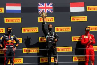 Mercedes' British driver Lewis Hamilton (C) celebrates with his trophy with second-placed Red Bull's Dutch driver Max Verstappen (L) and third-placed Ferrari's Monegasque driver Charles Leclerc on the podium after the Formula One British Grand Prix at the Silverstone motor racing circuit in Silverstone, central England on August 2, 2020. - Lewis Hamilton survived a dramatic finale to win the British Grand Prix on Sunday, just making it across the line on three tyres to beat a fast closing Max Verstappen on Red Bull. The defending world champion claimed his seventh British Grand Prix win as Ferarri's Charles Leclerc came third and Daniel Ricciardo of Renault fourth. (Photo by Frank Augstein / POOL / AFP) (Photo by FRANK AUGSTEIN/POOL/AFP via Getty Images)