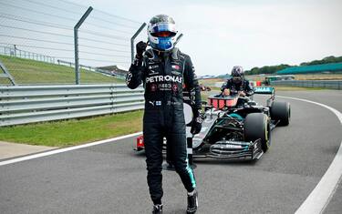 Mercedes' Finnish driver Valtteri Bottas celebrates in the pit lane after taking pole position as Mercedes' British driver Lewis Hamilton (back) gets out of his car during the qualifying session of the F1 70th Anniversary Grand Prix at Silverstone on August 8, 2020 in Northampton. - This weekend's race will commemorate the 70th anniversary of the inaugural world championship race, held at Silverstone in 1950. (Photo by ANDREW BOYERS / POOL / AFP) (Photo by ANDREW BOYERS/POOL/AFP via Getty Images)